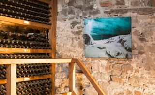 Multi-wine level wine/bottle racks with a painting on the wall of someone in a snow field.
