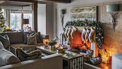 Christmas stockings hanging from a mantelpiece with lit candles in a candlestick in front of the mirror.