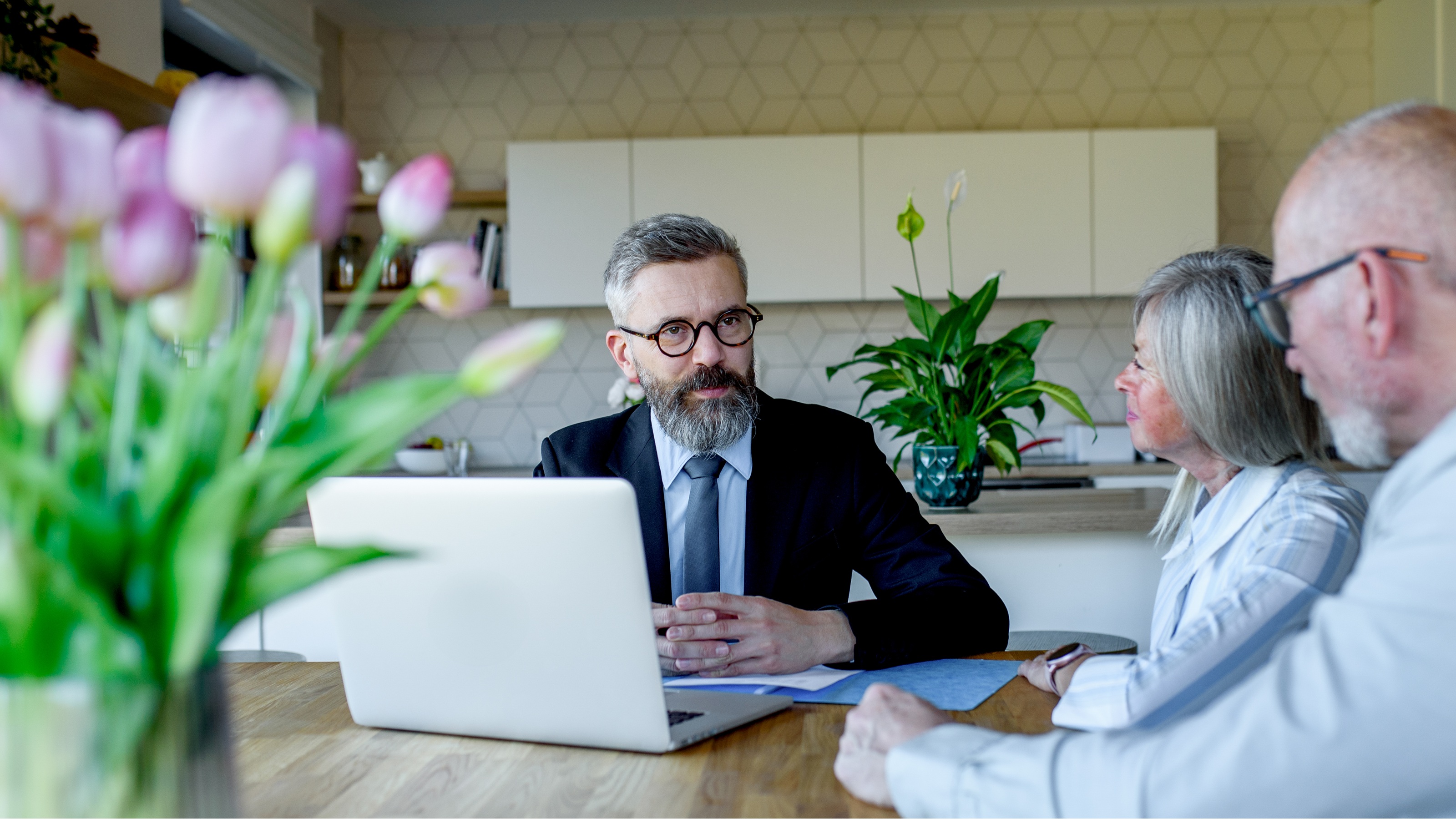 A financial adviser meets with older clients at their dining room table.