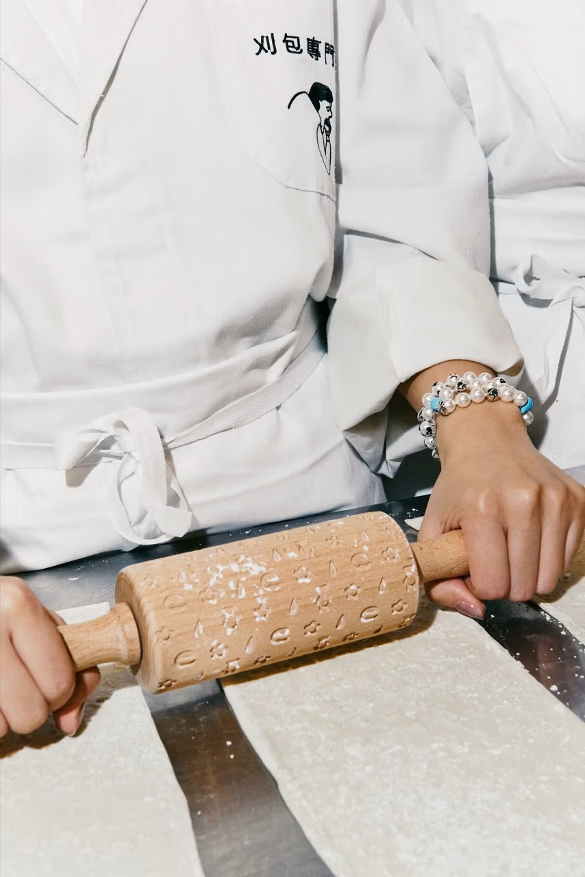 A series of fashion shots of young people wearing restaurant merchandise in white with black logos inside a brightly lit restaurant.