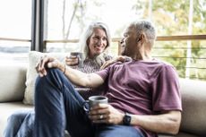 Senior couple having coffee and embracing on back porch of vacation home