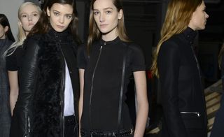 Models pose in line, wearing black clothing
