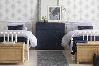 Coastal wallpaper in blue and white kids' bedroom with blue chest, gold accents, prints and wicker storage chests