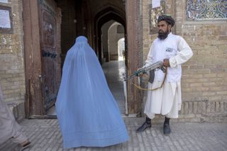 A Taliban fighter and a woman in a full covering in Afghanistan