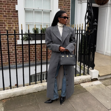 Marilyn wearing a grey coat, blue jeans and pointed boots