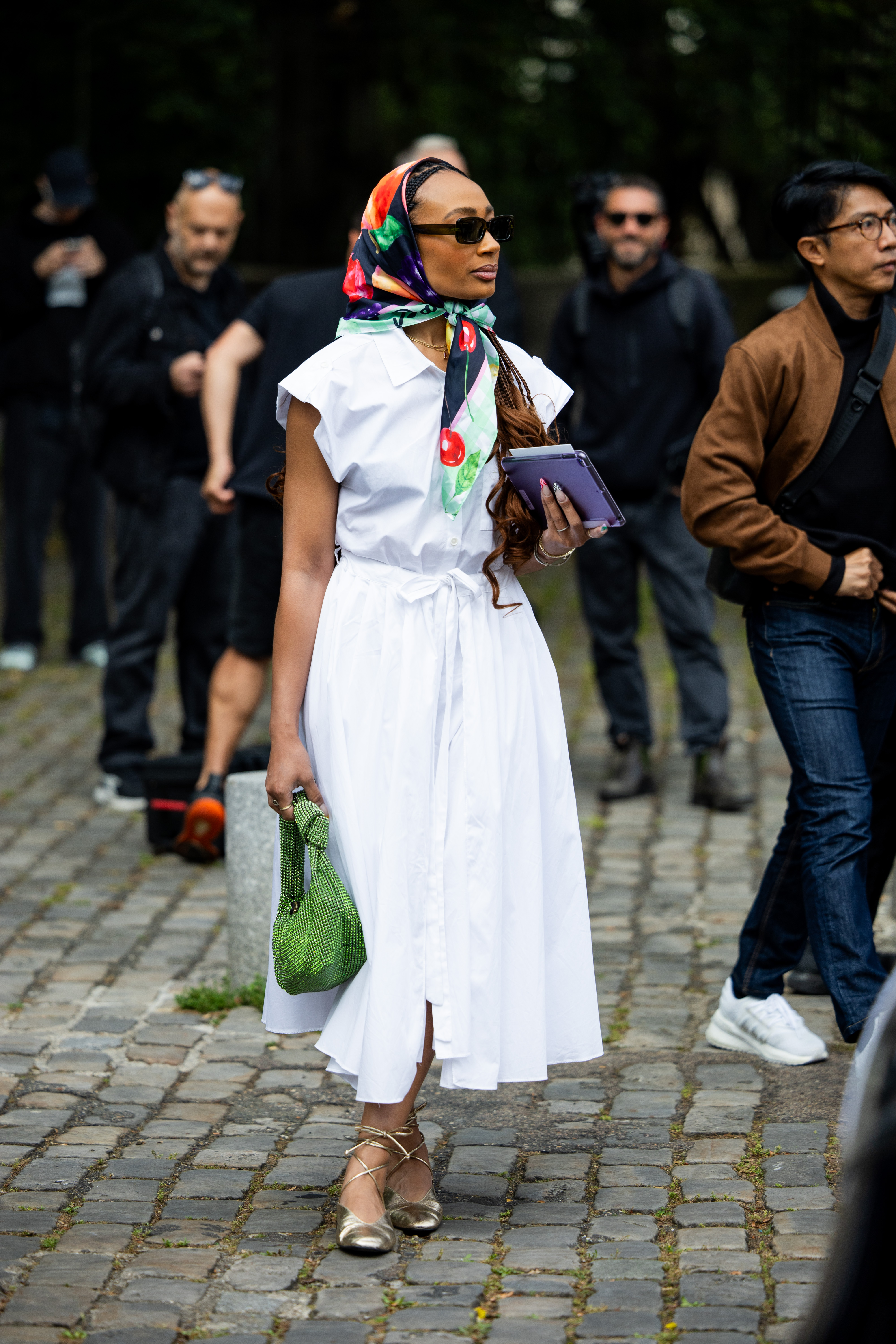 A guest wears white sleeveless shirt, skirt, head scarf, green bag outside Issey Miyake during the Menswear Spring/Summer 2025 as part of Paris Fashion Week on June 20, 2024 in Paris, France. (