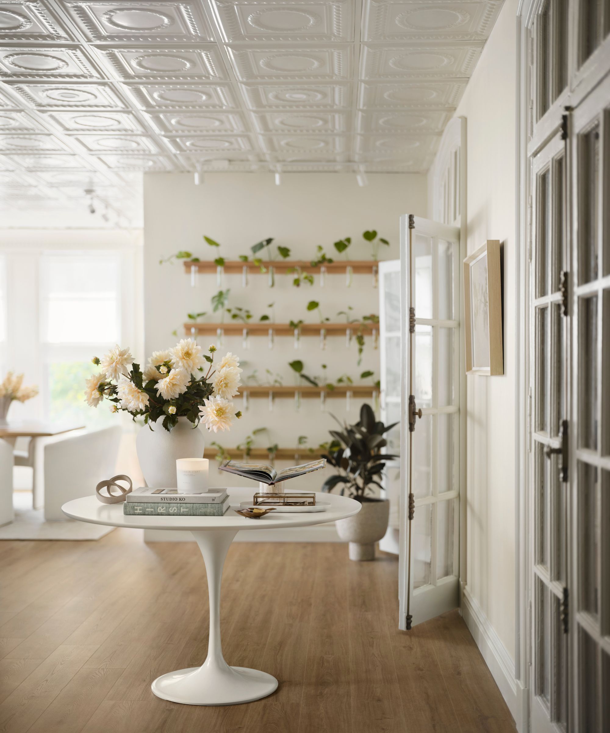 Office with cream walls, glass doors, moulded ceilings, round white table with vase and books