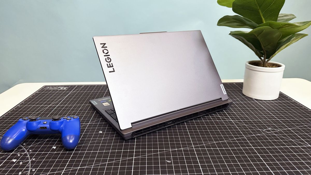 The Lenovo Legion 5i Gen 9 seen from behind on a gray desk mat beside a potted plant and a game controller
