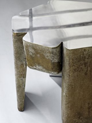 A close-up of a stool with brown legs and a metallic top.
