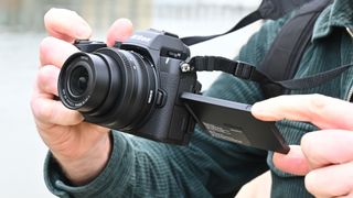 Man holding Nikon Z50 II with rear screen tilted