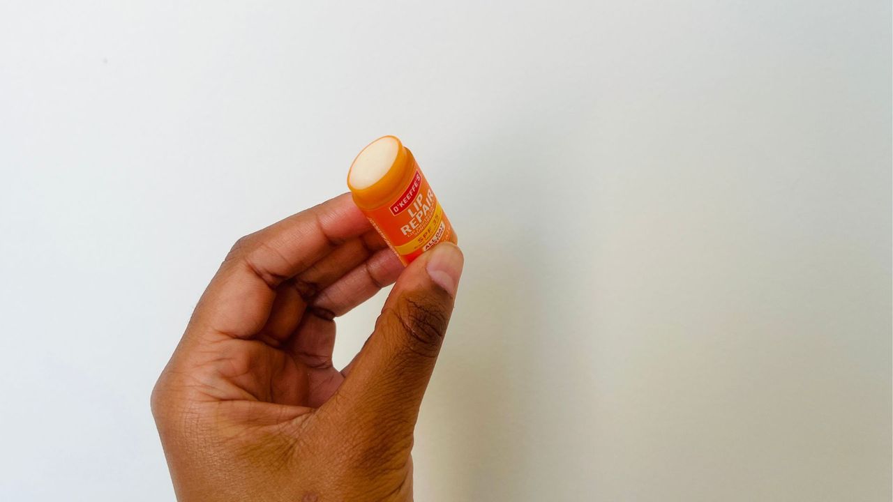 A person holding an opened O'Keeffe's SPF lip balm.