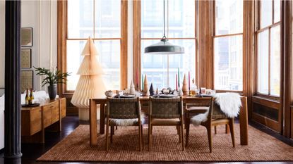 Honeycomb paper Christmas tree in cream styled inside of a bright dining room area with floor-to-ceiling window panes and low-slung mid-century furniture