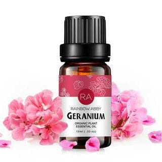 Geranium Essential Oil in amber glass bottle with pink flowers around it on a white background