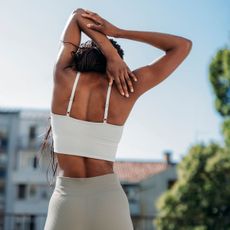 A woman doing some of the best exercises for back pain, stretching her hand behind her back