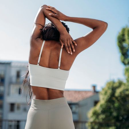 A woman doing some of the best exercises for back pain, stretching her hand behind her back