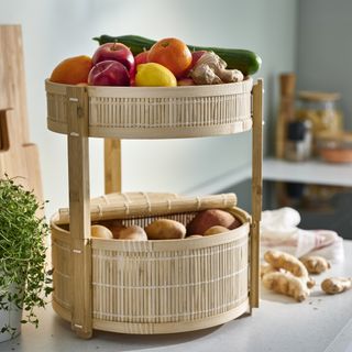 Bamboo food storage basket on kitchen counter, filled with potatoes, and other produce