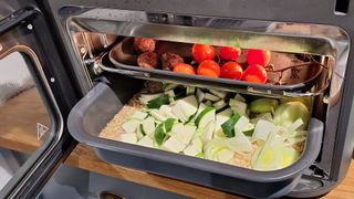 Tomatoes and raw vegetables being added into the Ninja Combi cooker mid-cook