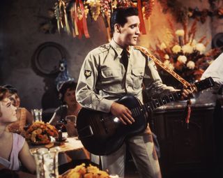 Elvis Presley wearing an Army uniform playing a guitar in the movie G.I. Blues