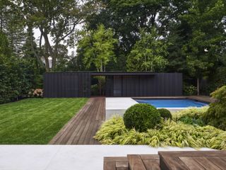 Garden with swimming pool and grass surrounded by trees