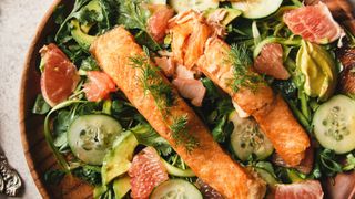 Salmon sitting on plate of salad with gut healthy foods