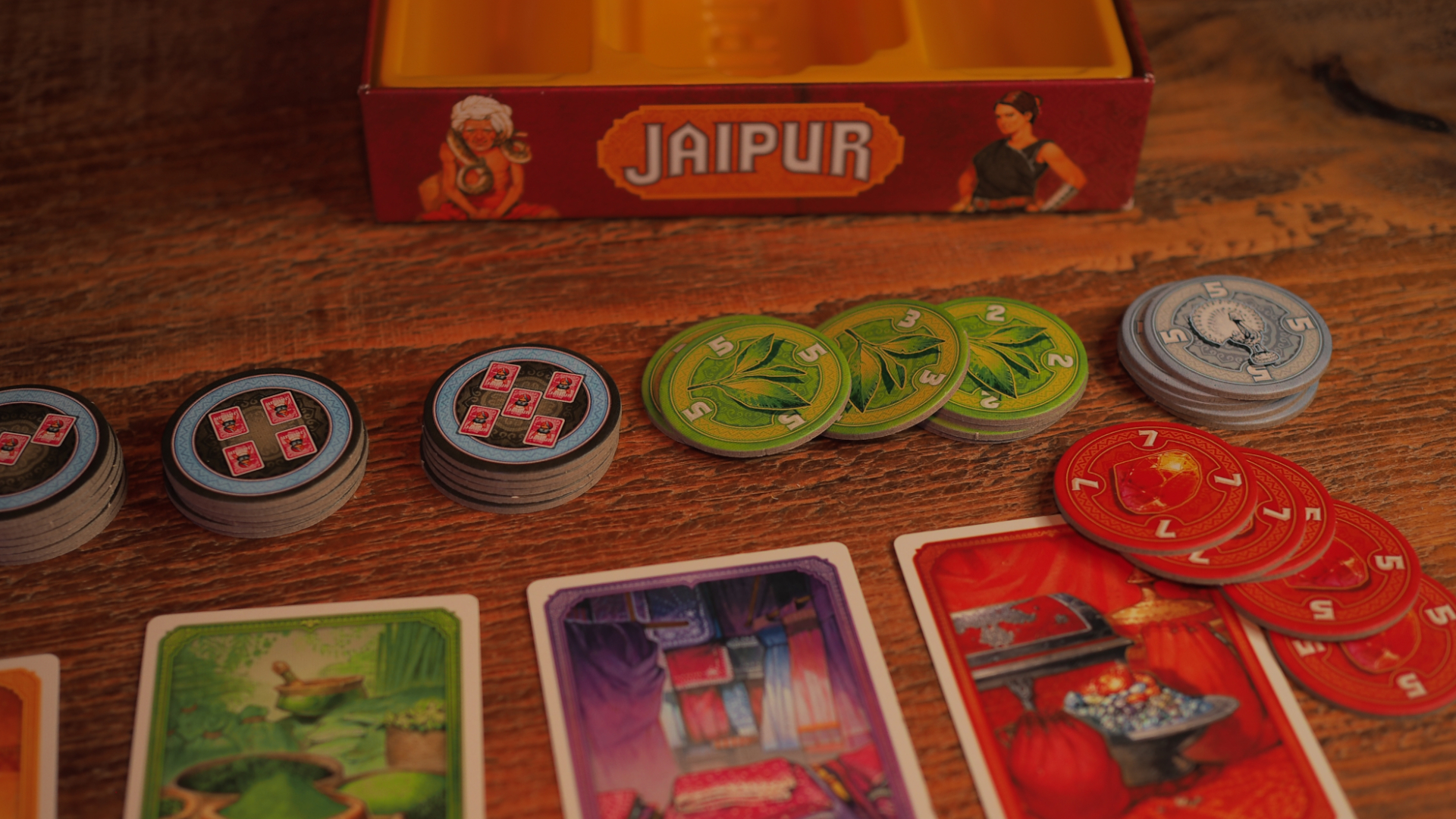 Jaipur box, cards, and tokens laid out on a wooden table