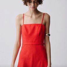 A model wearing a strappy red Mango dress with a silver arm bangle