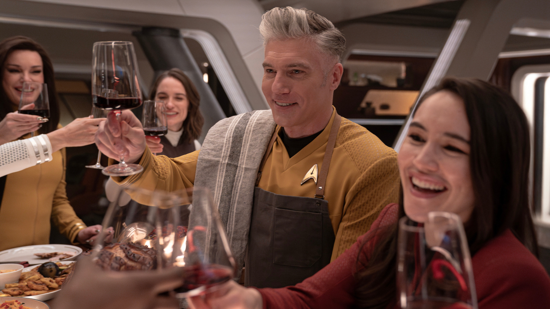 Sci-fi characters partying on a spaceship. Left to right: Rebecca Romijn as Una, Melanie Scrofano as Batel, Anson Mount as Capt. Pike and Christina Chong as Laían in season 3 , Episode 7 of Strange New Worlds