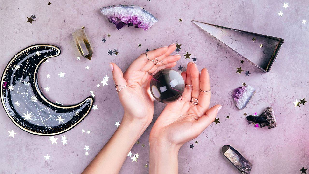woman's hands holding crystal ball with other crystals surrounding