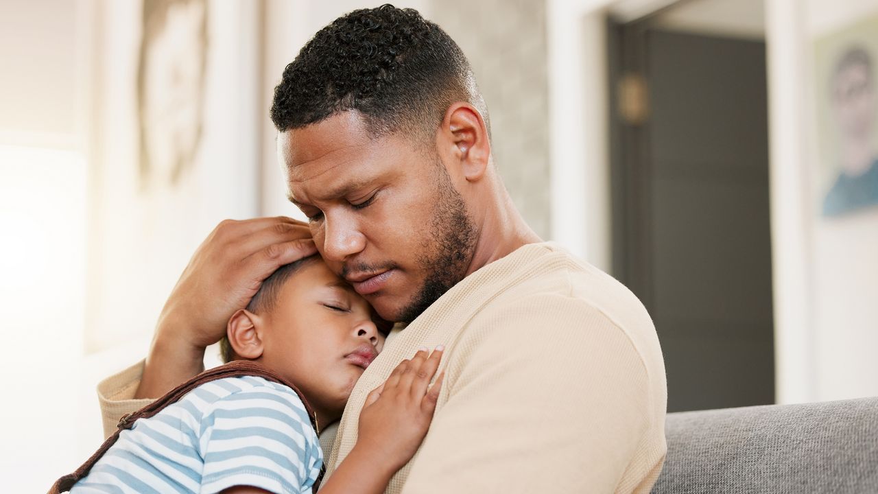 A worried-looking father holds his young son close.