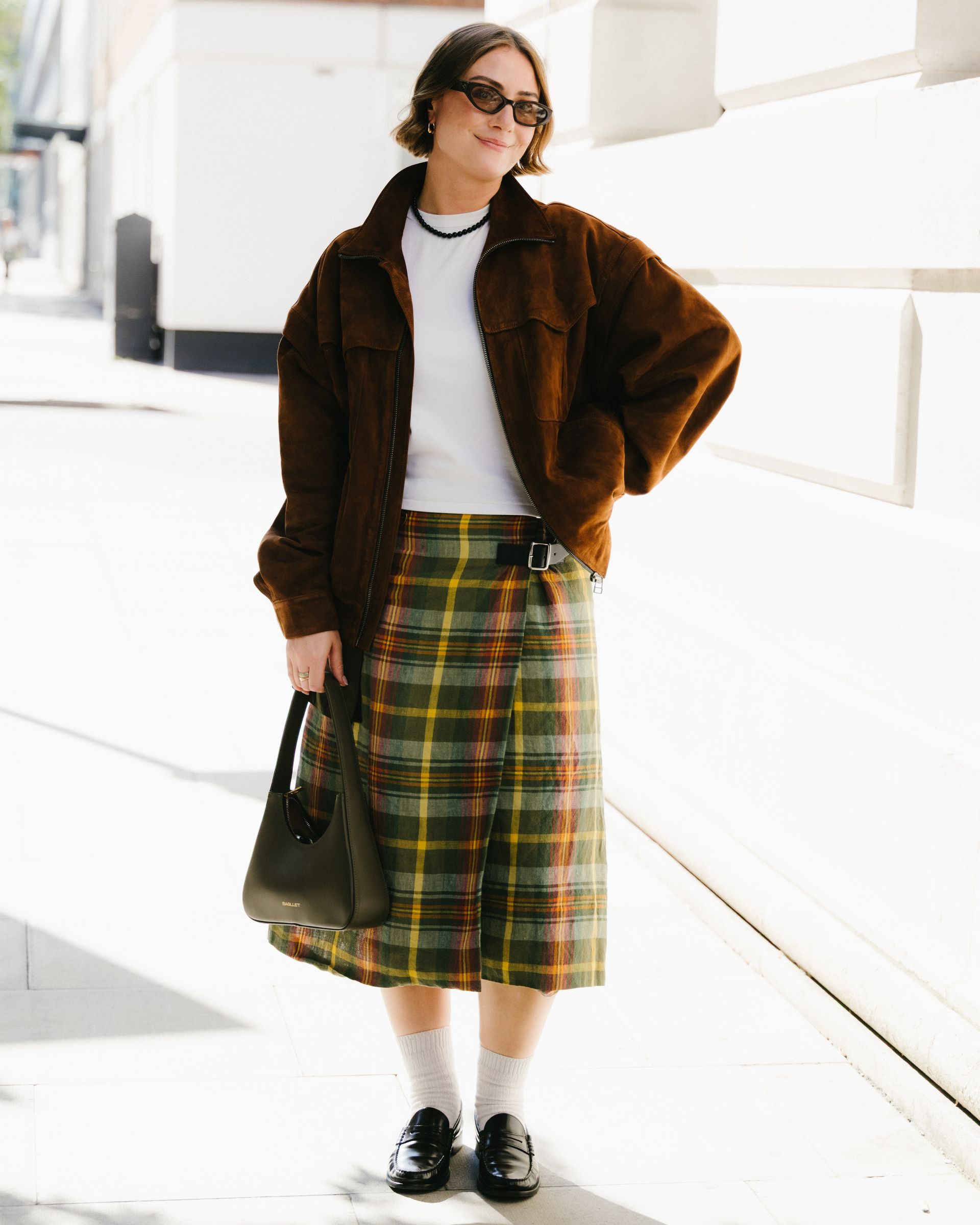 A woman in London wears a skirt with socks and loafers.
