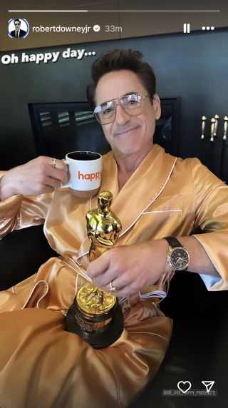 Robert Downey Jr. holding Oscar and cup of coffee while wearing robe