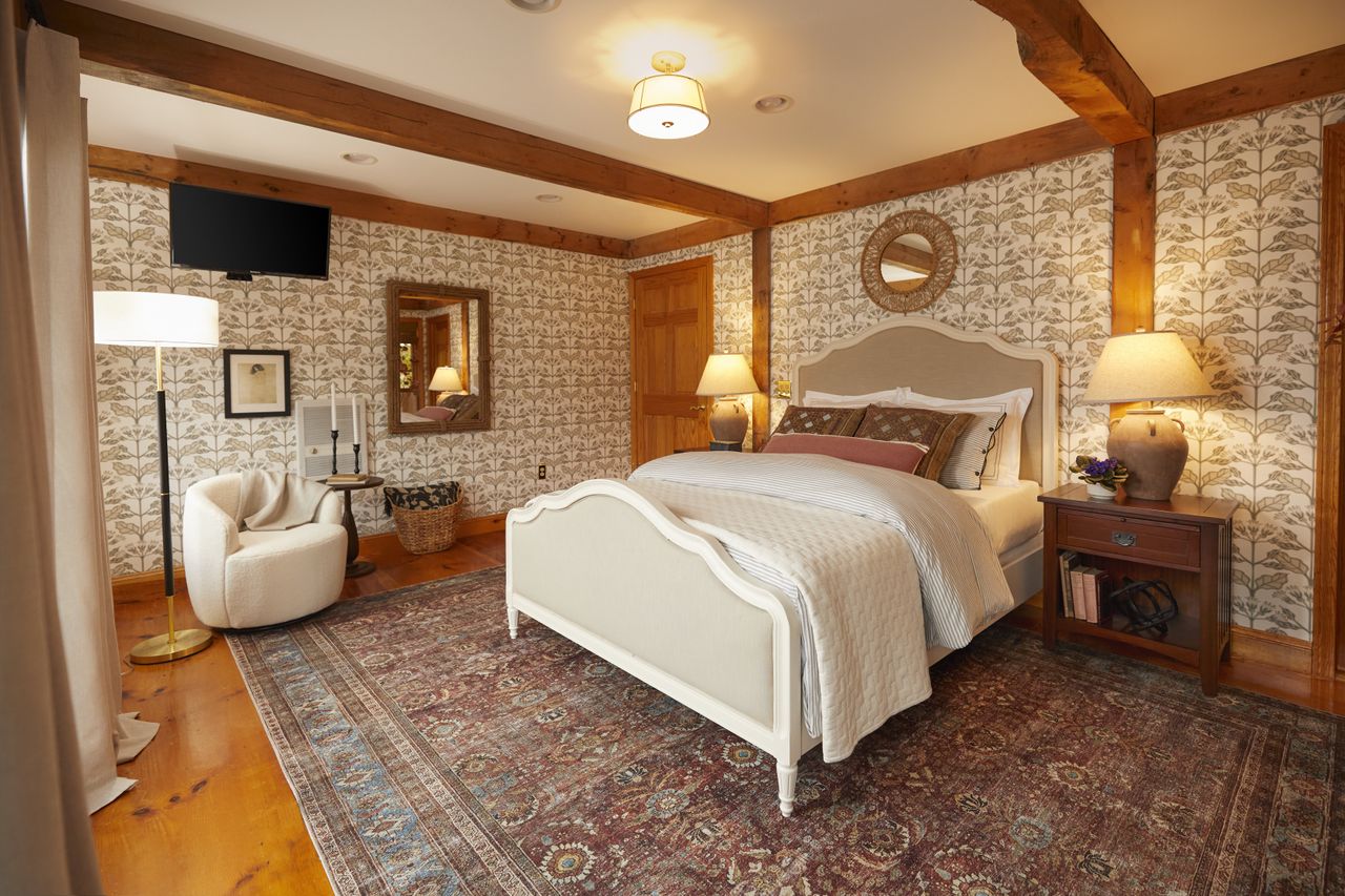 A bedroom with a double bed and botanical leaf patterned wallpaper