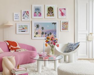 A modern living room with brightly colored framed wall art and bright pink velvet sofa