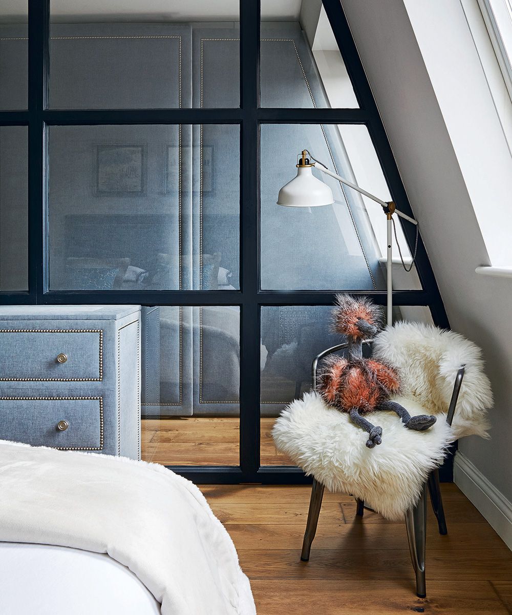 A glass partition wall screening off gray small bedroom storage.