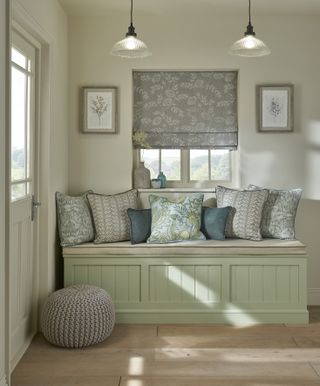 cream hallway with green painted bespoke bench with cushion, cushions on top, artwork and blind