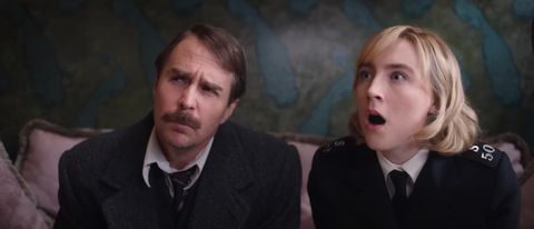 Sam Rockwell sits sternly as Saoirse Ronan looks stunned next to him in See How They Run.