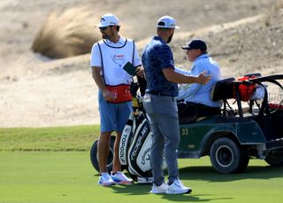 Rahm complains to a rules official in a golf buggy