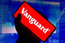 Vanguard logo on smartphone with stock chart in background
