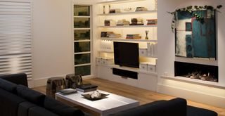 white living room with bespoke built-in shelves with integrated media and TV to show how to make a living room look expensive