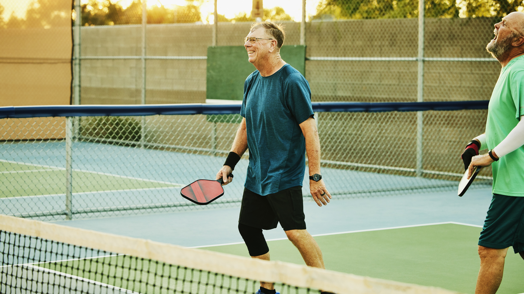 Two men on pickleball court smiling and laughing