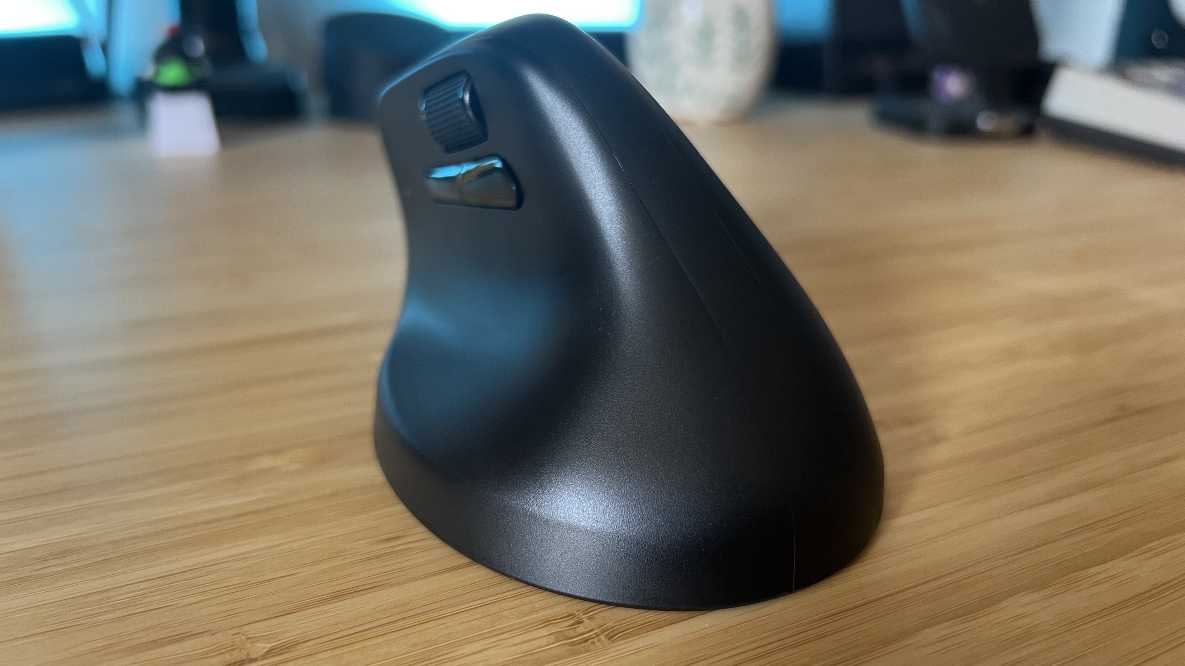 Back of Keychron M5 gaming mouse, showing wide base and left side buttons on a wooden table