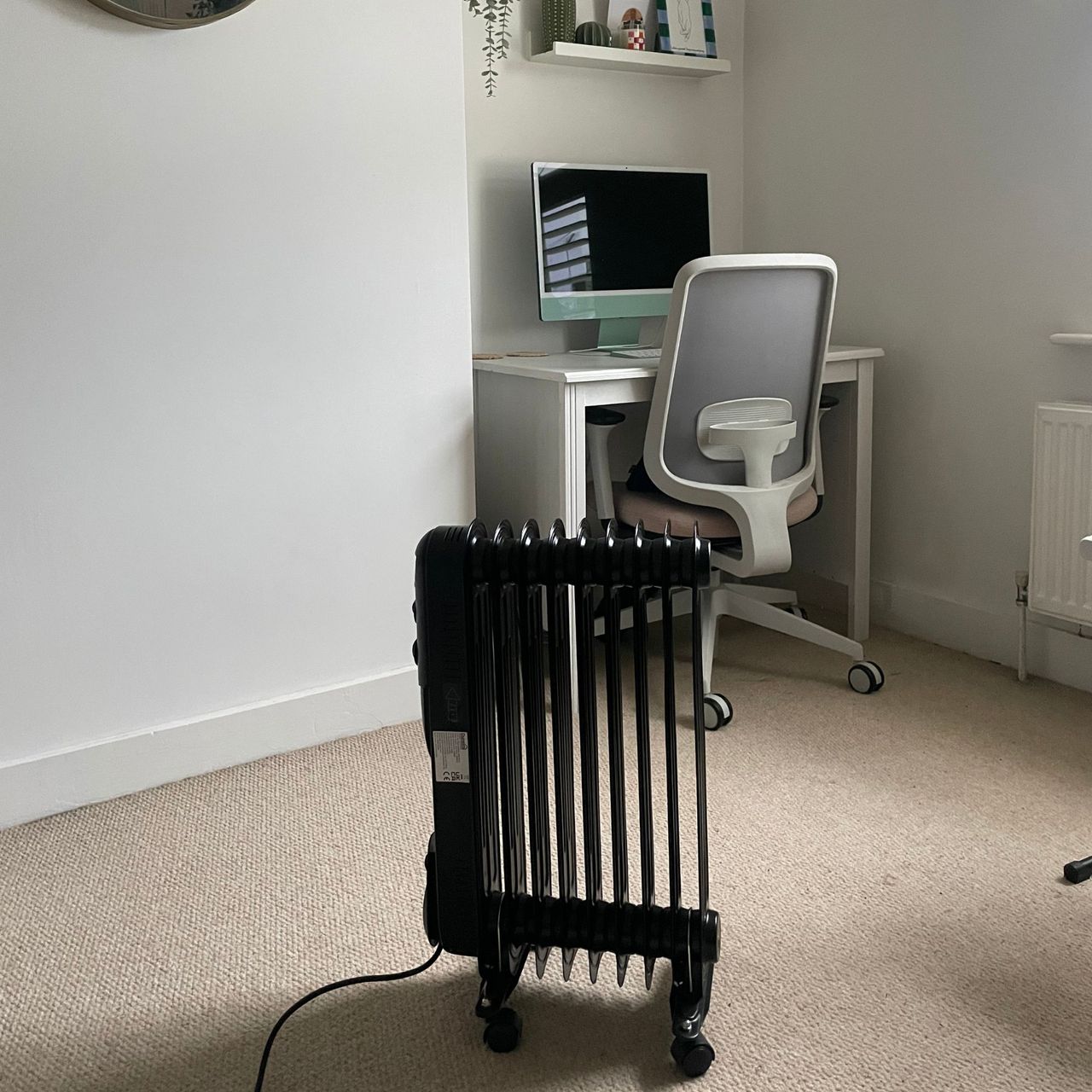 Dunelm oil-filled radiator standing in a white office area with a desk behind it