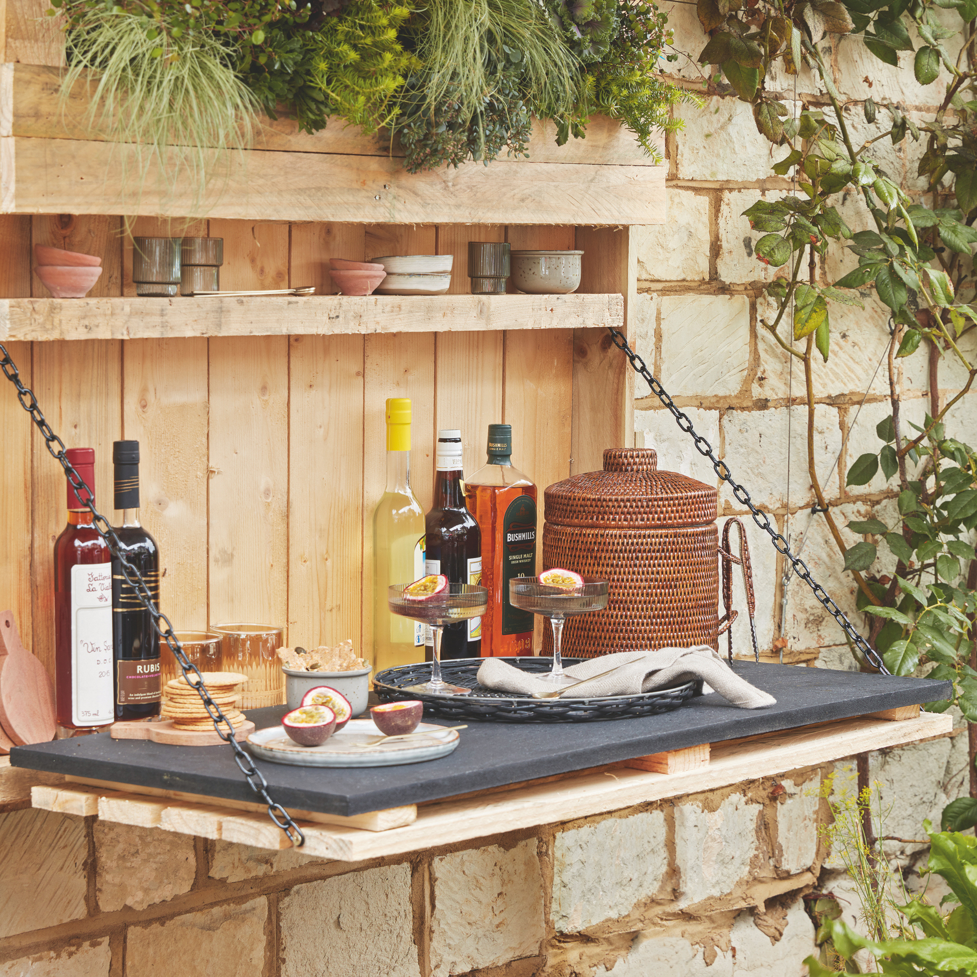 A fold down bar attached to the stone wall with a shelf and storage. Rattan ice bucket and passion fruit martini.