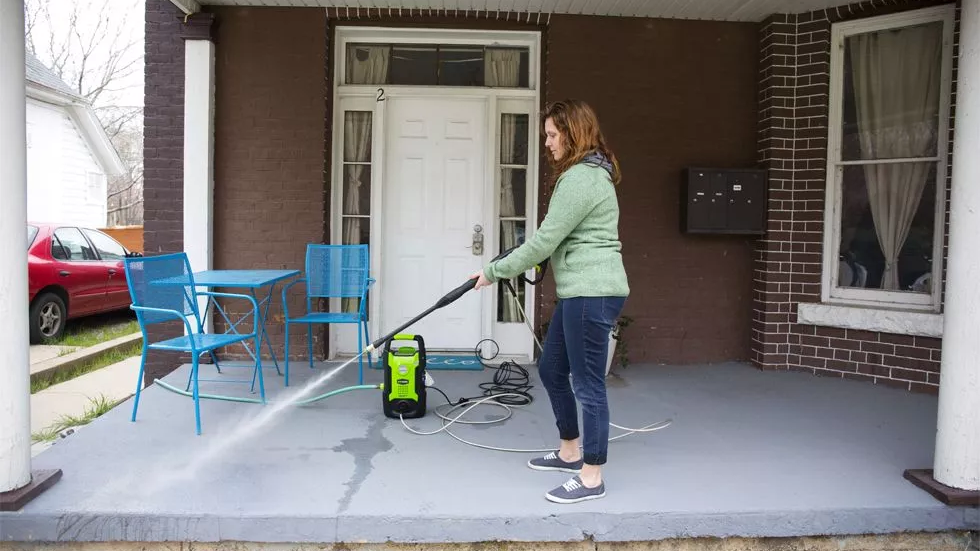 a woman using the Greenworks GPW1501 to clean a porch