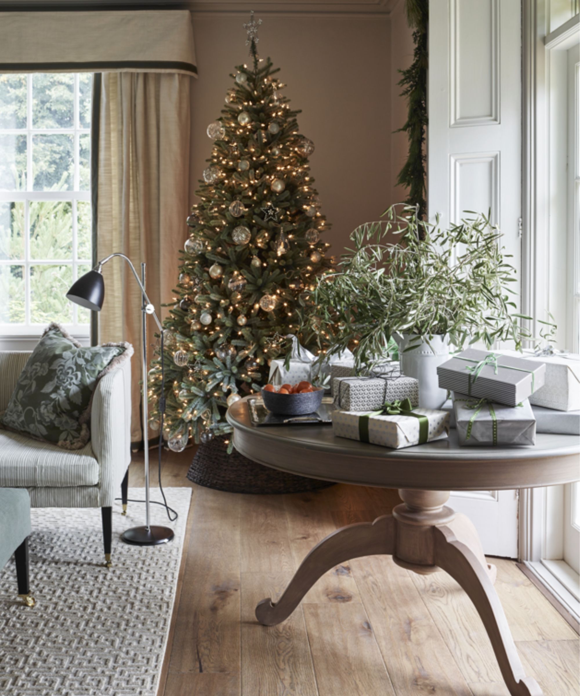 Christmas tree behind round table covered with gifts