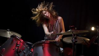 Girl in stripey top plays the drums