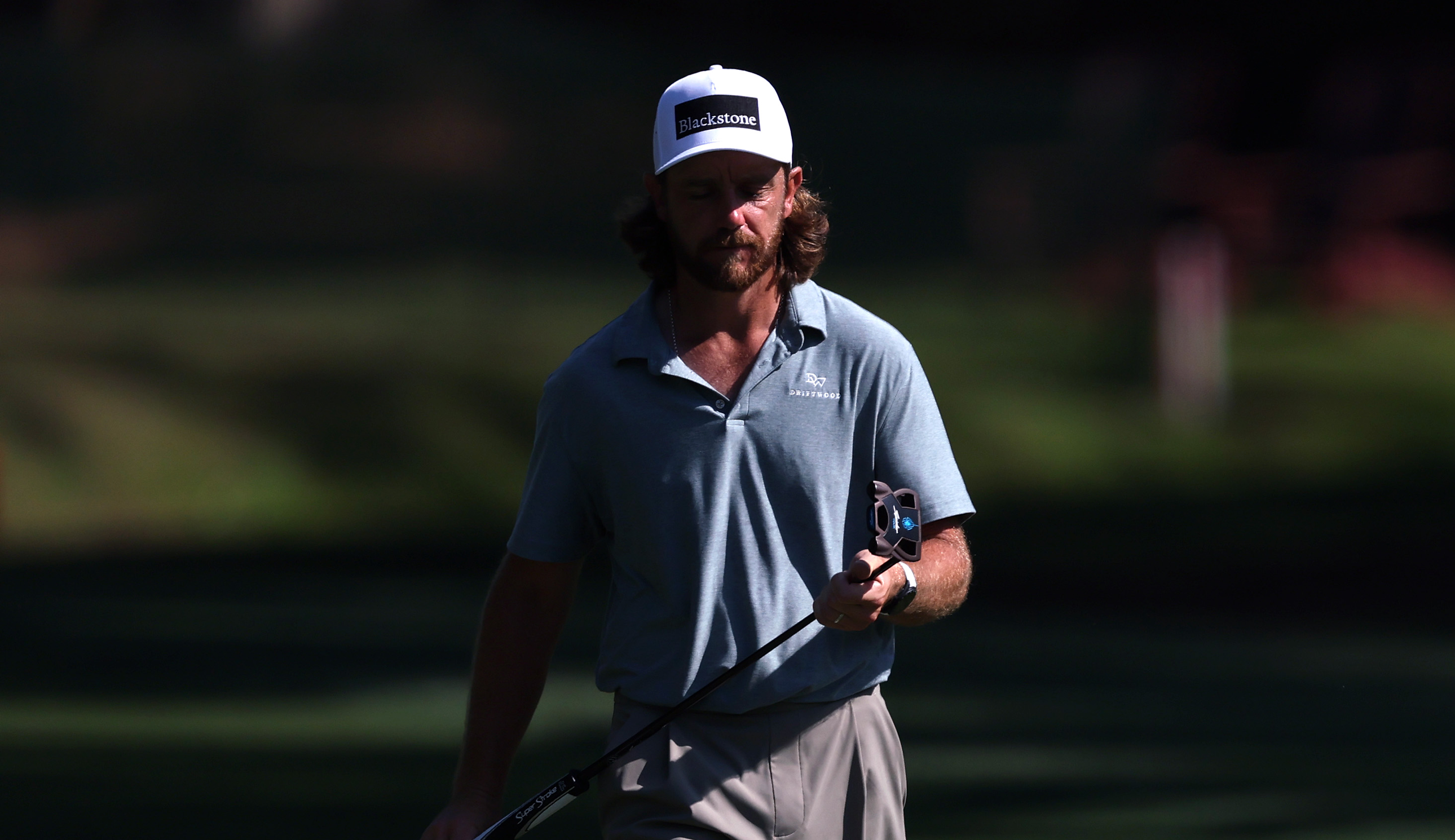 Tommy Fleetwood walks to the green holding a putter