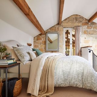bedroom with white wall and wooden beam with pillows on bed and blanket