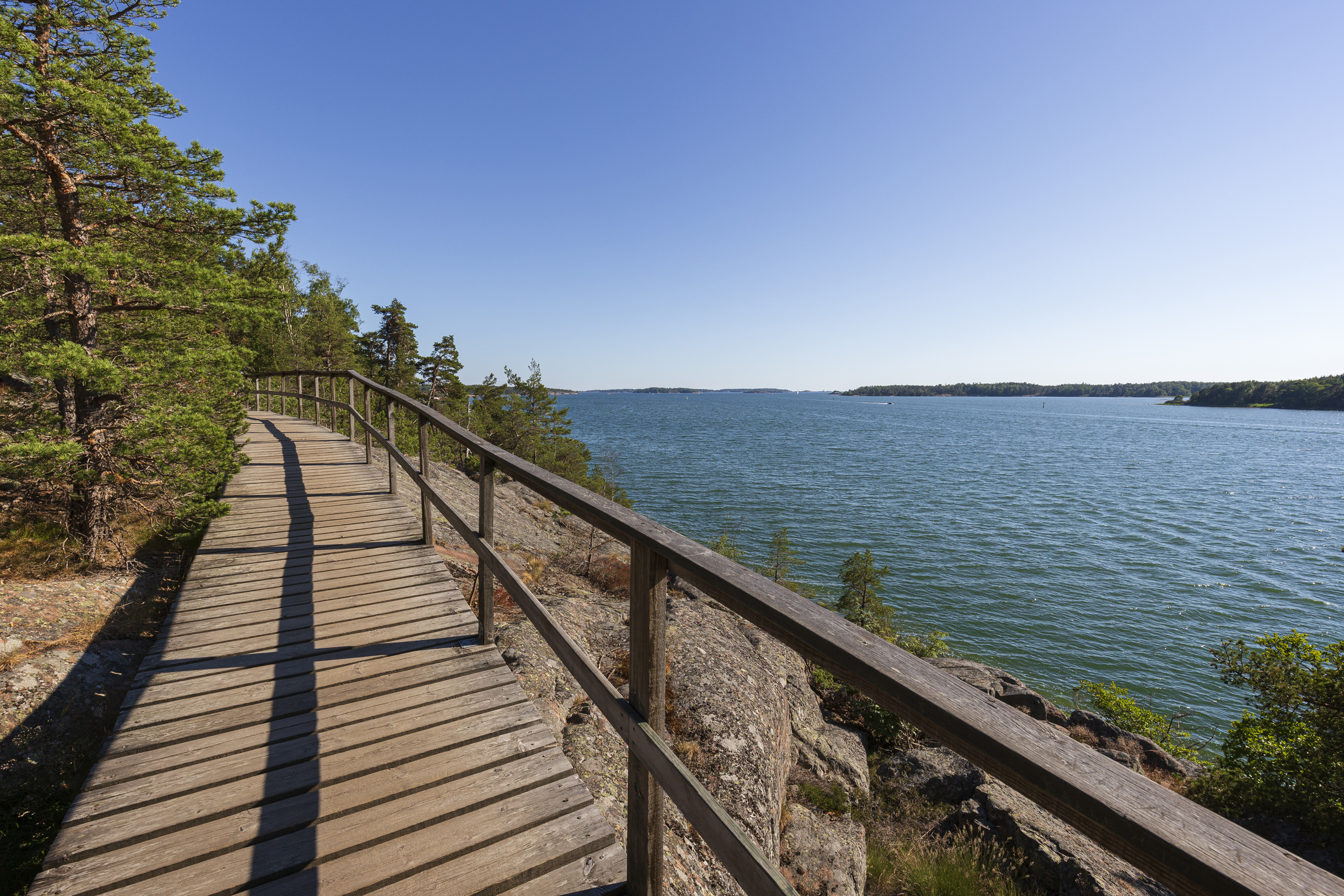 Elevated wooden seaside walkway on a cliff by the Baltic sea in Mariehamn, Åland Islands, Finland, on a sunny day in the summer. 