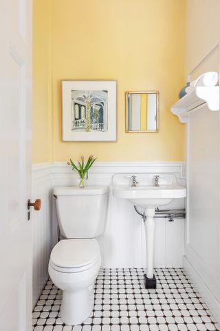 A bathroom with yellow walls, and half white walls